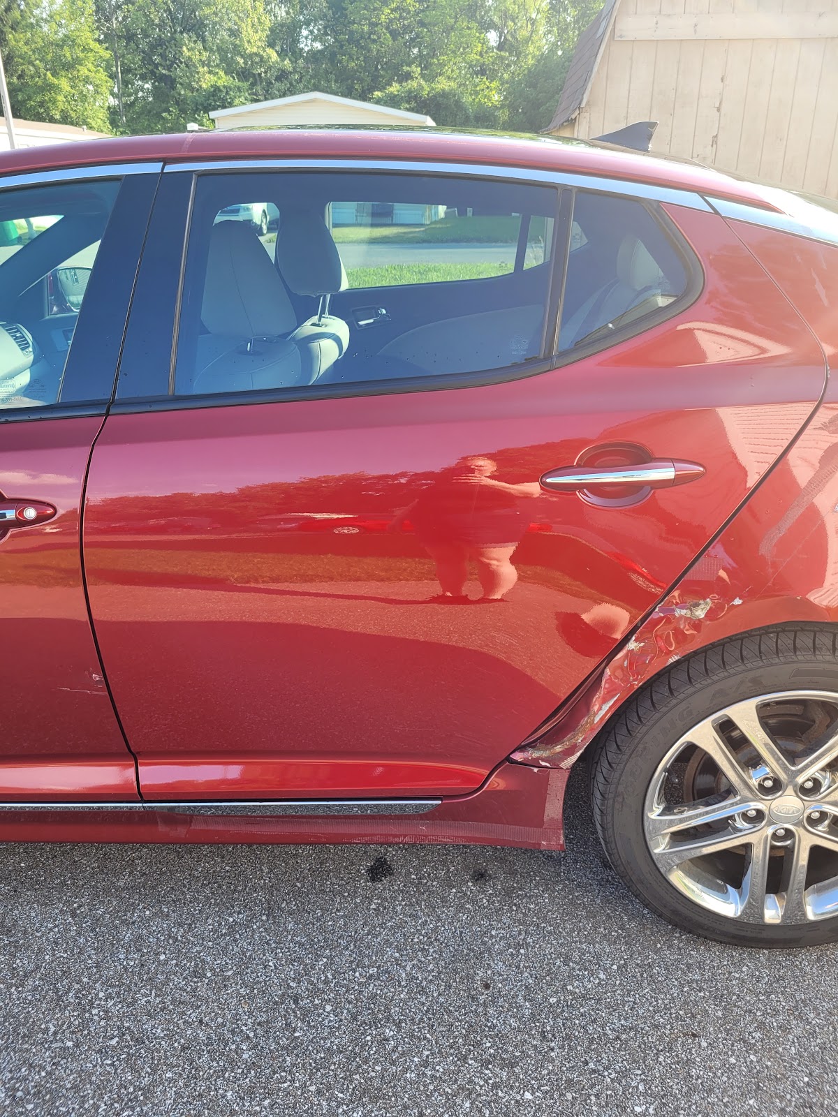 Close-up of dent and scrape damage on a car's rear quarter panel before repair